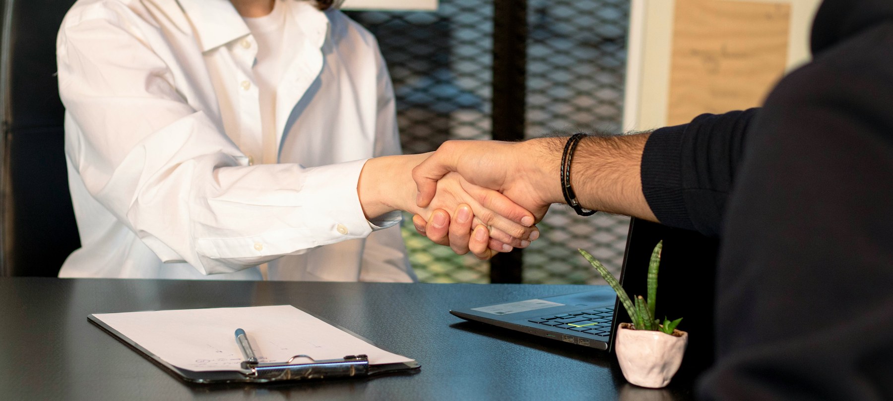 Handshake across a desk over paperwork