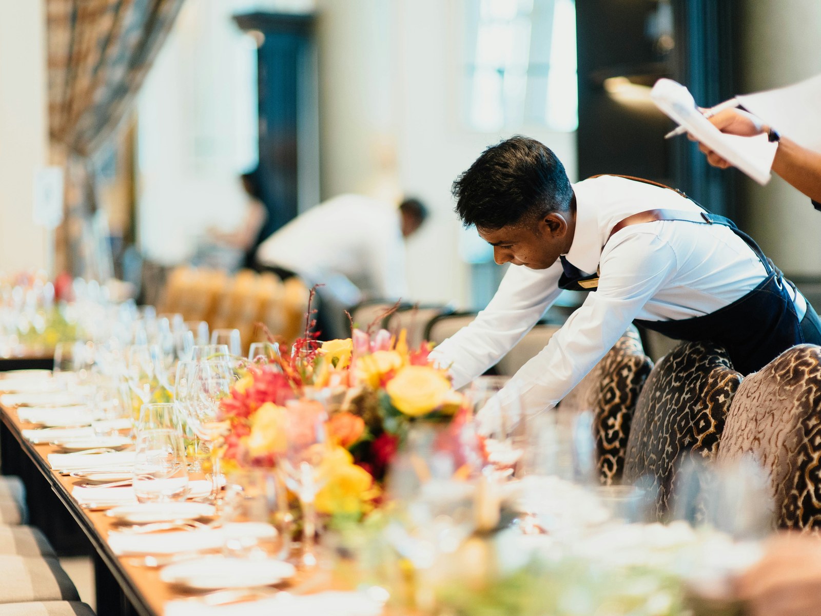 Waiter setting a long table before service